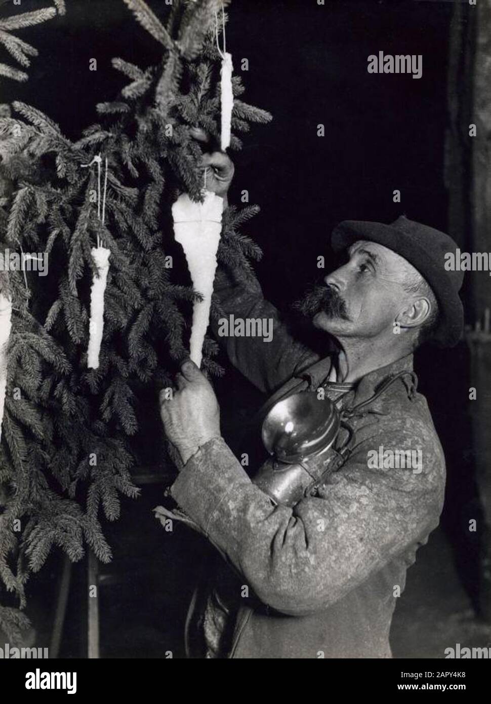 Weihnachtsnacht/Weihnachtsfeier in einer Salzmine in Deutschland, 1933 SCHMÜCKT EIN Bergmann mit Hartmetalllampe den Weihnachtsbaum mit Salzkristallen. Stockfoto