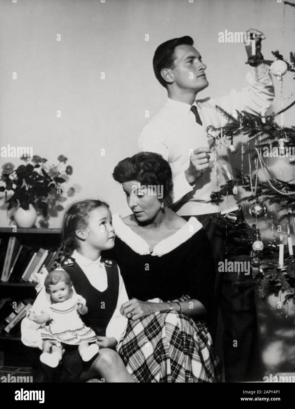 Das Familientheater, Weihnachten. Vater, Mutter, Tochter und Puppe in Partykleidung am Weihnachtsbaum. Niederlande, 1950-1960. Stockfoto