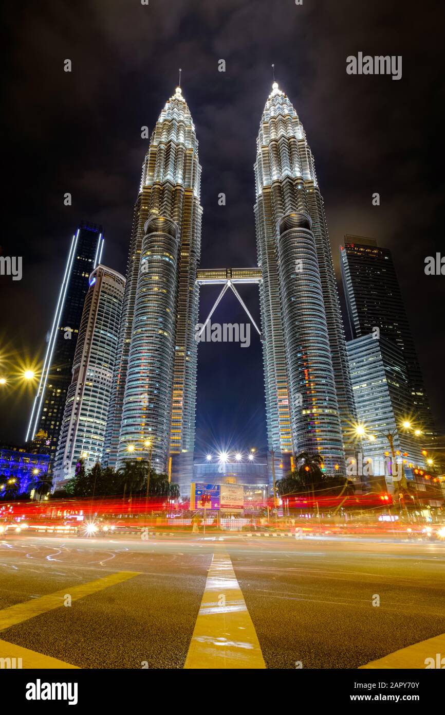 Kuala LUMPUR, MALAYSIA - JANJUARY 12.2020: Nahaufnahme des KLCC Petronas Twin Tower in der Nacht aus tiefem Winkel am Straßenrand mit leichtem Pfad. Stockfoto