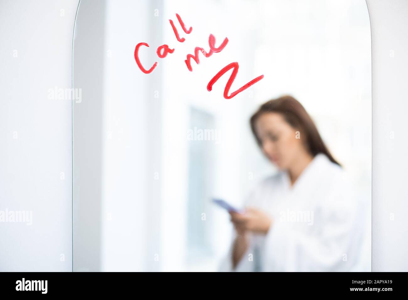 Teil des Spiegels mit der Bitte um Anruf geschrieben mit Lippenstift und Reflexion des Mädchens Stockfoto