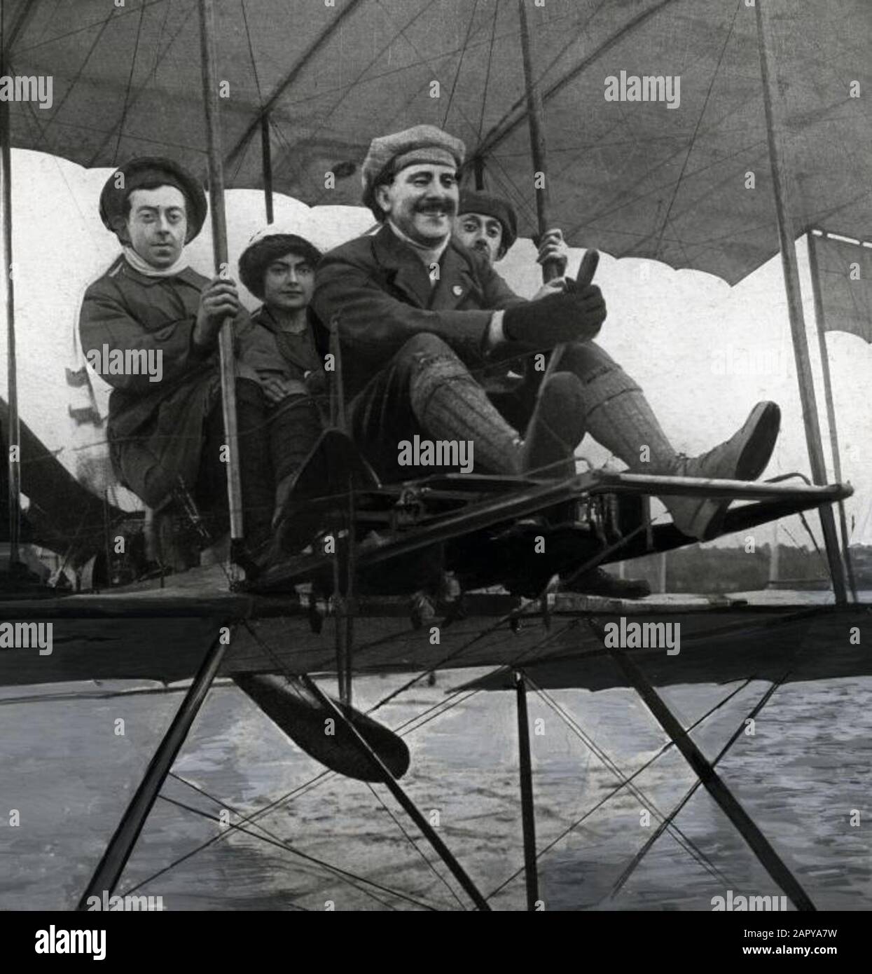 Der niederländische Flugzeughersteller Marinus van Meel (1880-1958) lacht über den Lenker eines völlig offenen Flugzeugs. Hinter ihm zwei Frauen und ein Mann. Soesterberg, 1911. Stockfoto