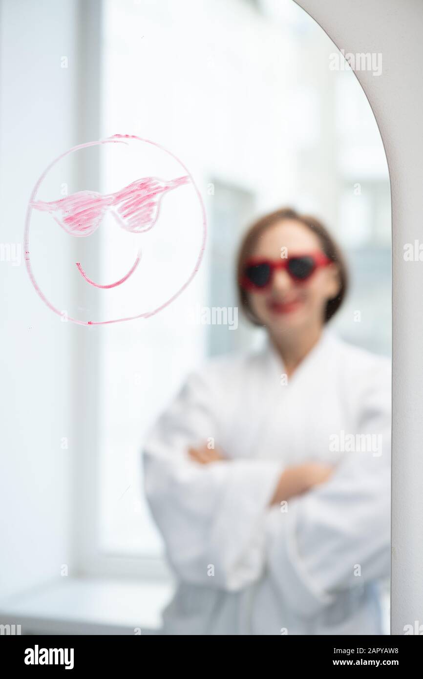 Gesicht mit Lächeln und Sonnenbrille, gezeichnet mit Lippenstift und Spiegelung des glücklichen Mädchens Stockfoto