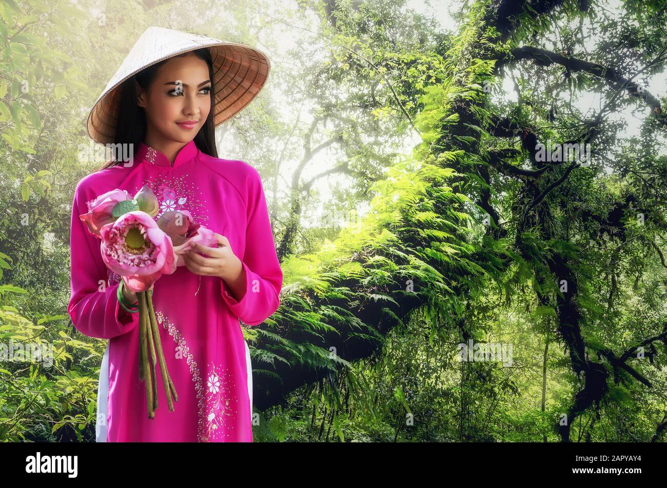 Porträt einer lächelnden jungen Frau mit langen Haaren, die ein traditionelles Kleid aus Vietnam trägt Stockfoto