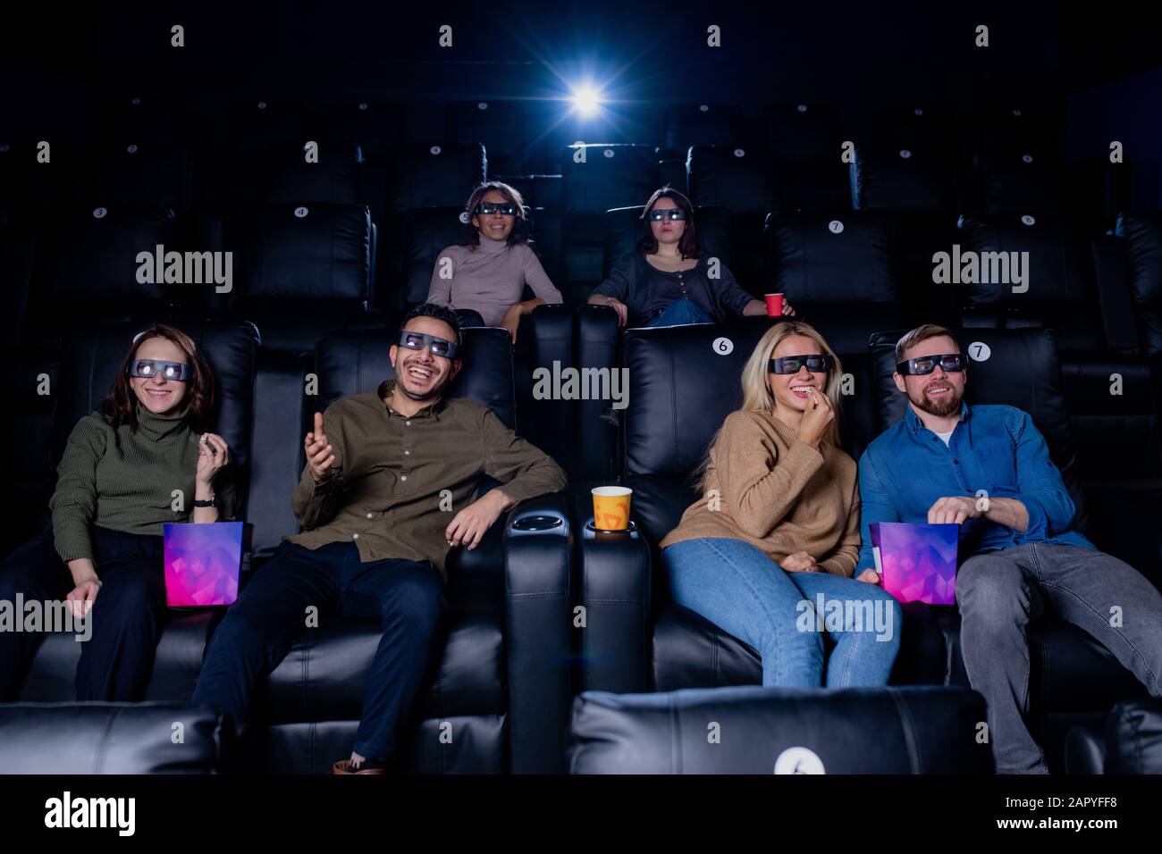 Große Gruppe glücklicher junger Freunde in 3D-Brillen, die ihre Freizeit im Kino verbringen Stockfoto