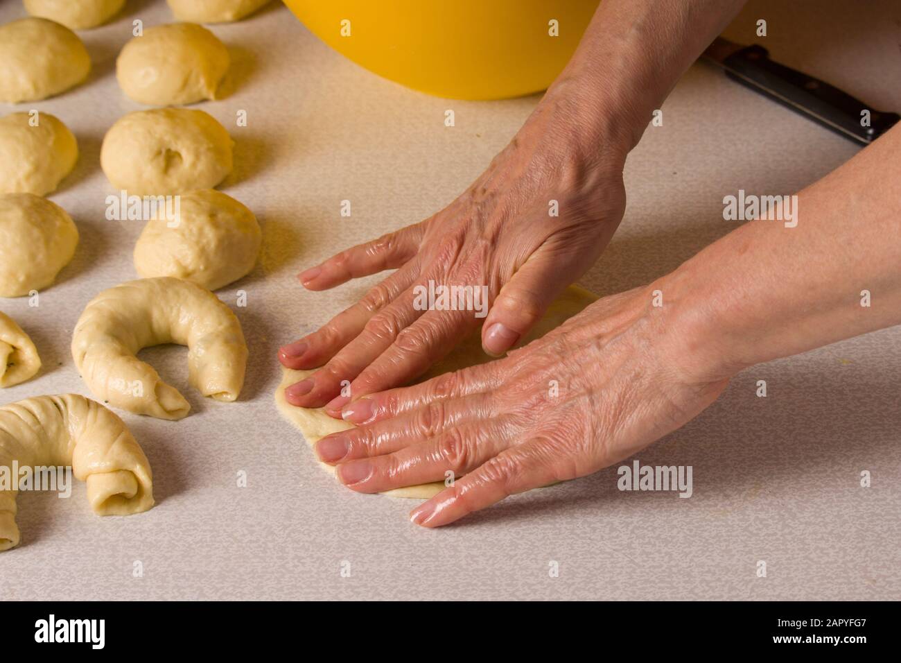 Die Hände der Frauen rollen den Teig auf einem Bagel. Stockfoto
