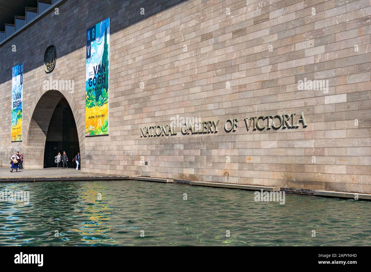 Melbourne, Australien - 18. April 2017: Eingangstür der National Gallery of Victoria mit bunten Bannern für neue Ausstellung und Wasserpool auf der Vorfahrt Stockfoto