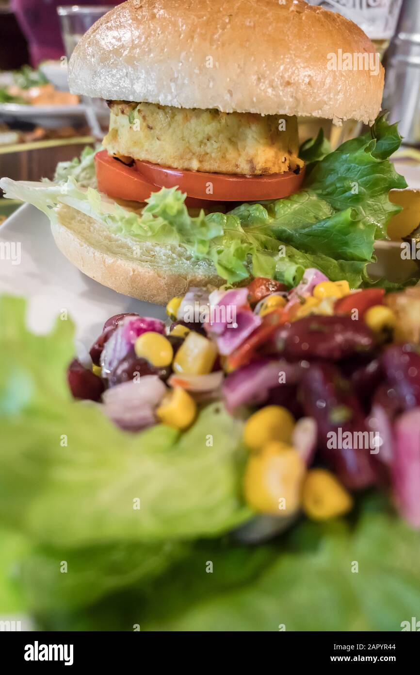 Gesunde vegane Burger mit Tomaten, gebackene Kartoffeln, Bohnen, Zwiebeln, Salat. Close-up. Stockfoto