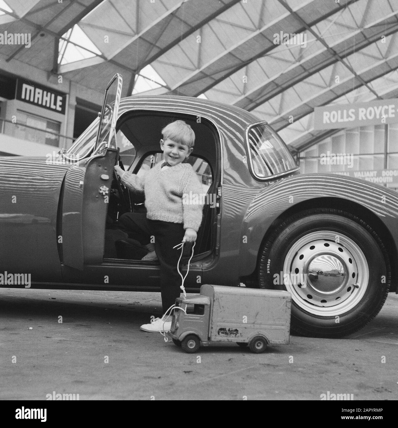 Maarten betrachtet das MG-Coupé mit seinem Spielzeugauto jetzt, da der RAI dahinter steht Datum: 13. Februar 1961 Schlagwörter: Spielzeugautos Institutionenname: Mg Stockfoto