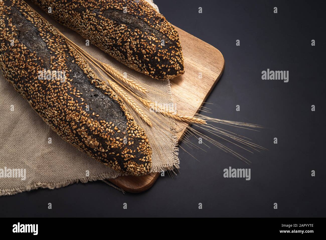 Hausgemachte Sauerteigbrot baguette auf vintage Handtuch auf schwarzen Hintergrund. Stockfoto