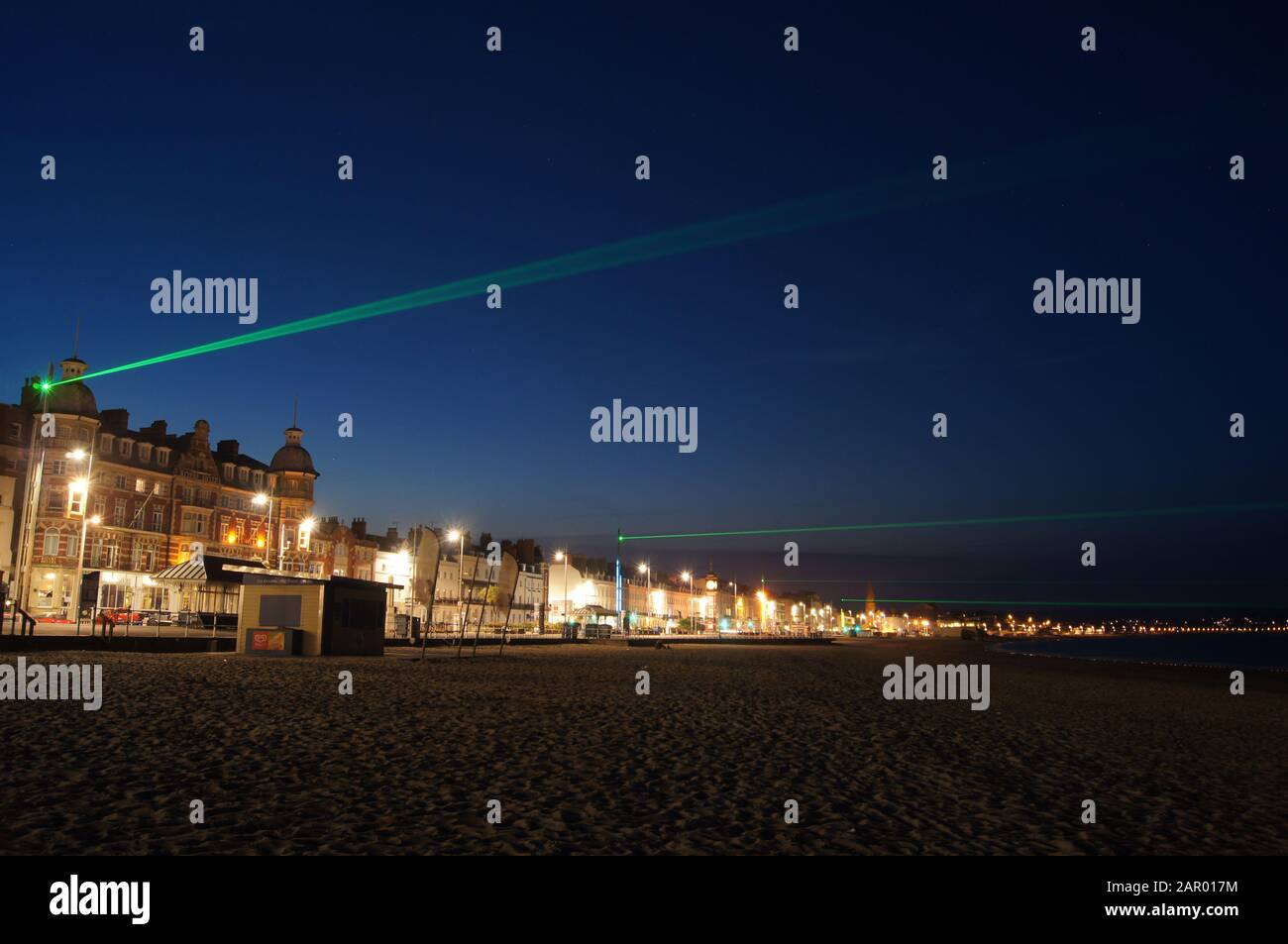 Grüne Laser an einer Meeresfront in Weymouth, Dorset. Stockfoto