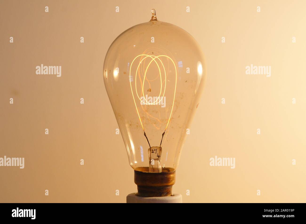 Eine sehr alte Glühlampe mit einem Kohlefilm, der bei niedrigem Strom leuchtet. Stockfoto