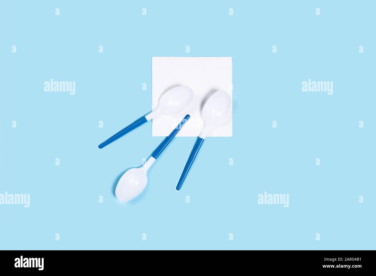 Muster aus weißem Kunststoff Löffel auf blauem Hintergrund. Vertikale Bild. Flach, Ansicht von oben. Stockfoto
