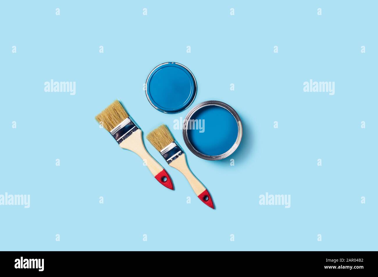 Foto für Wohnungsreparaturen. Blauer Hintergrund mit Farbe und zwei Holzquasten. Stockfoto