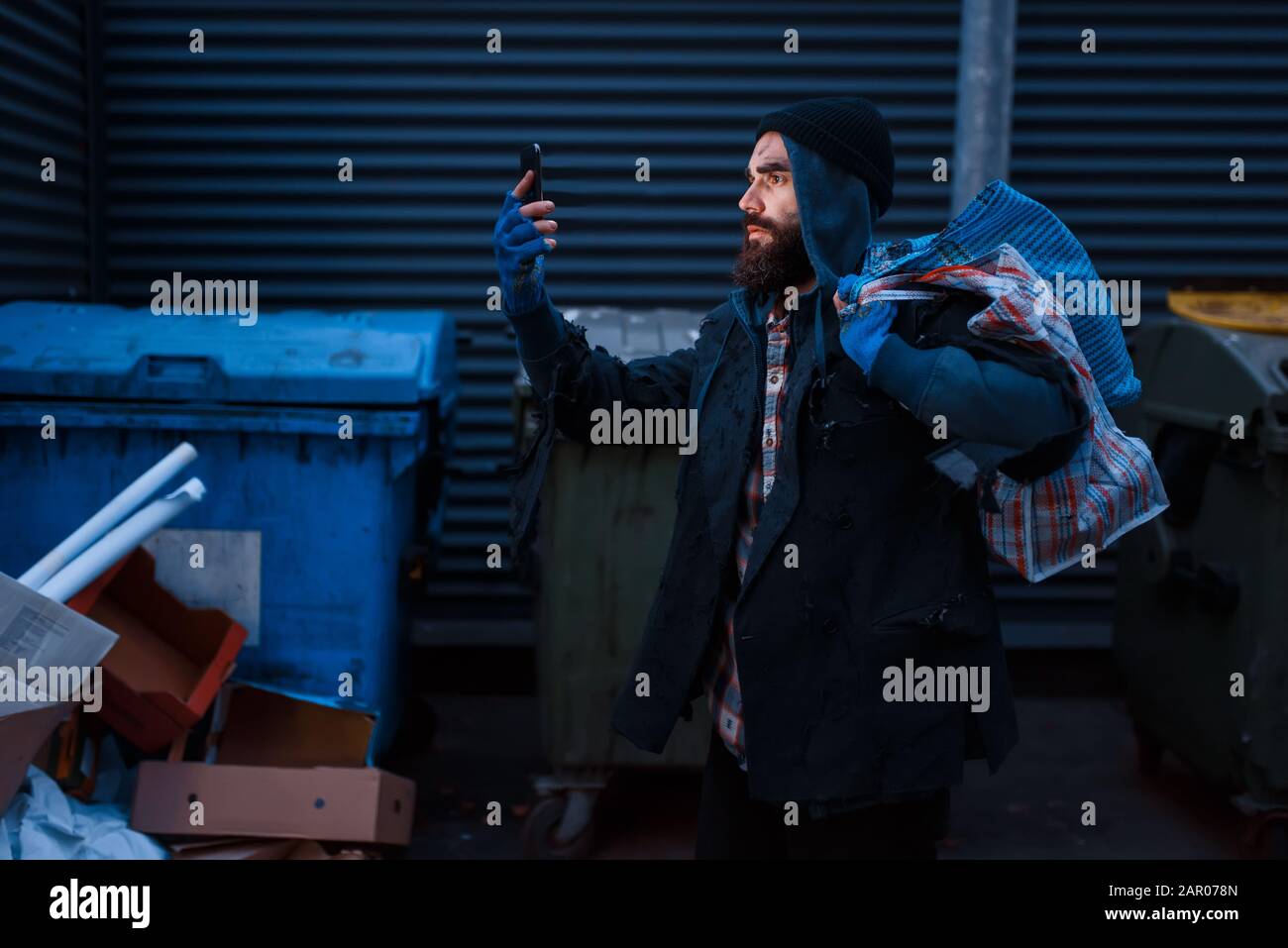 Glücklicher Bettler fand Handy in Trashcan Stockfoto