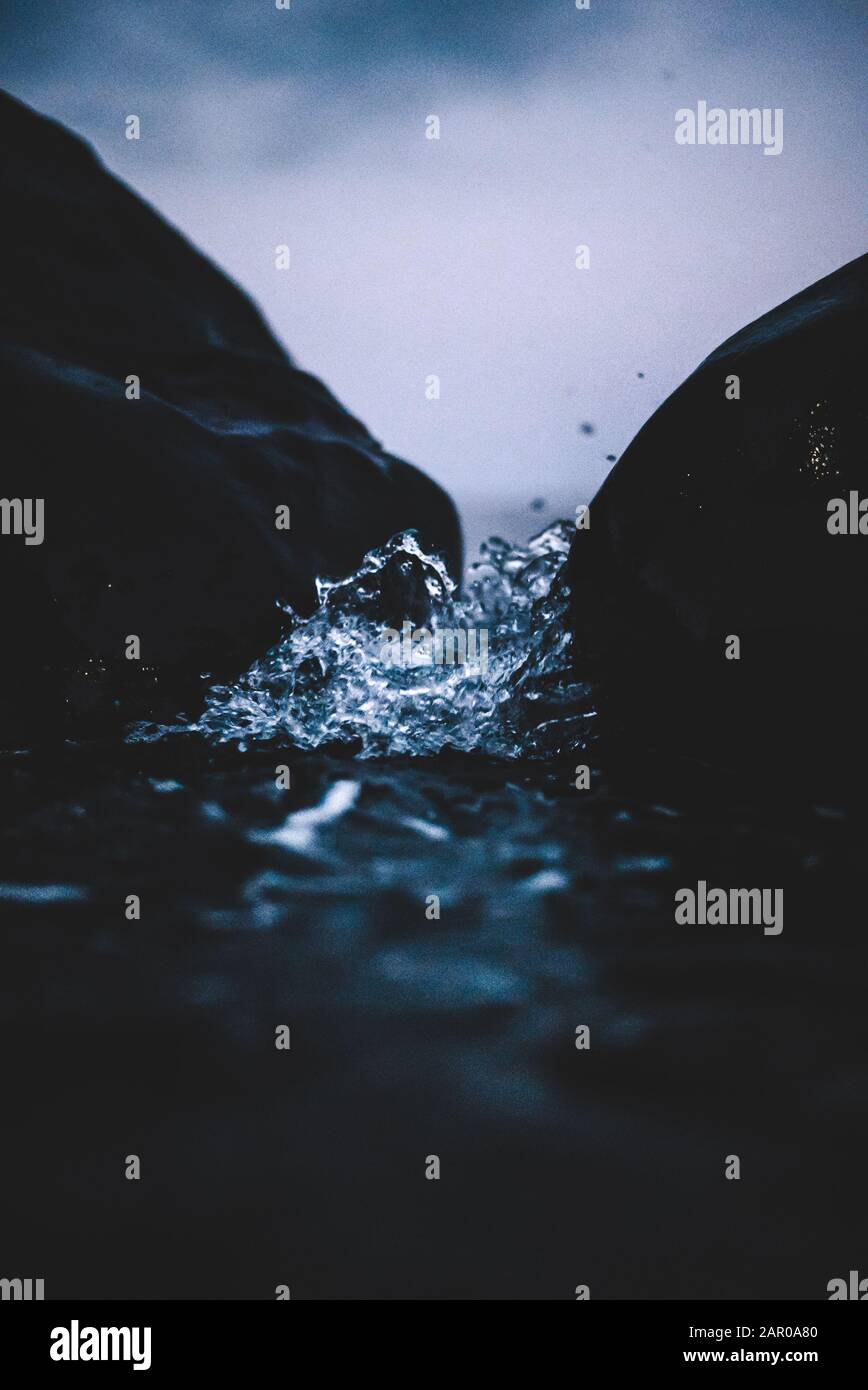 Wasser, das auf Felsen trifft und kleine Tropfen spritzen in die Kamera Stockfoto