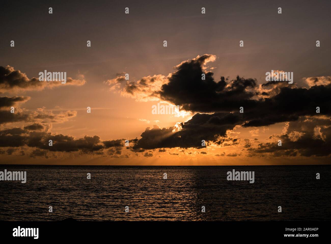 Sonnenuntergang über dem Meer mit großen Wolken vor der Sonne Stockfoto