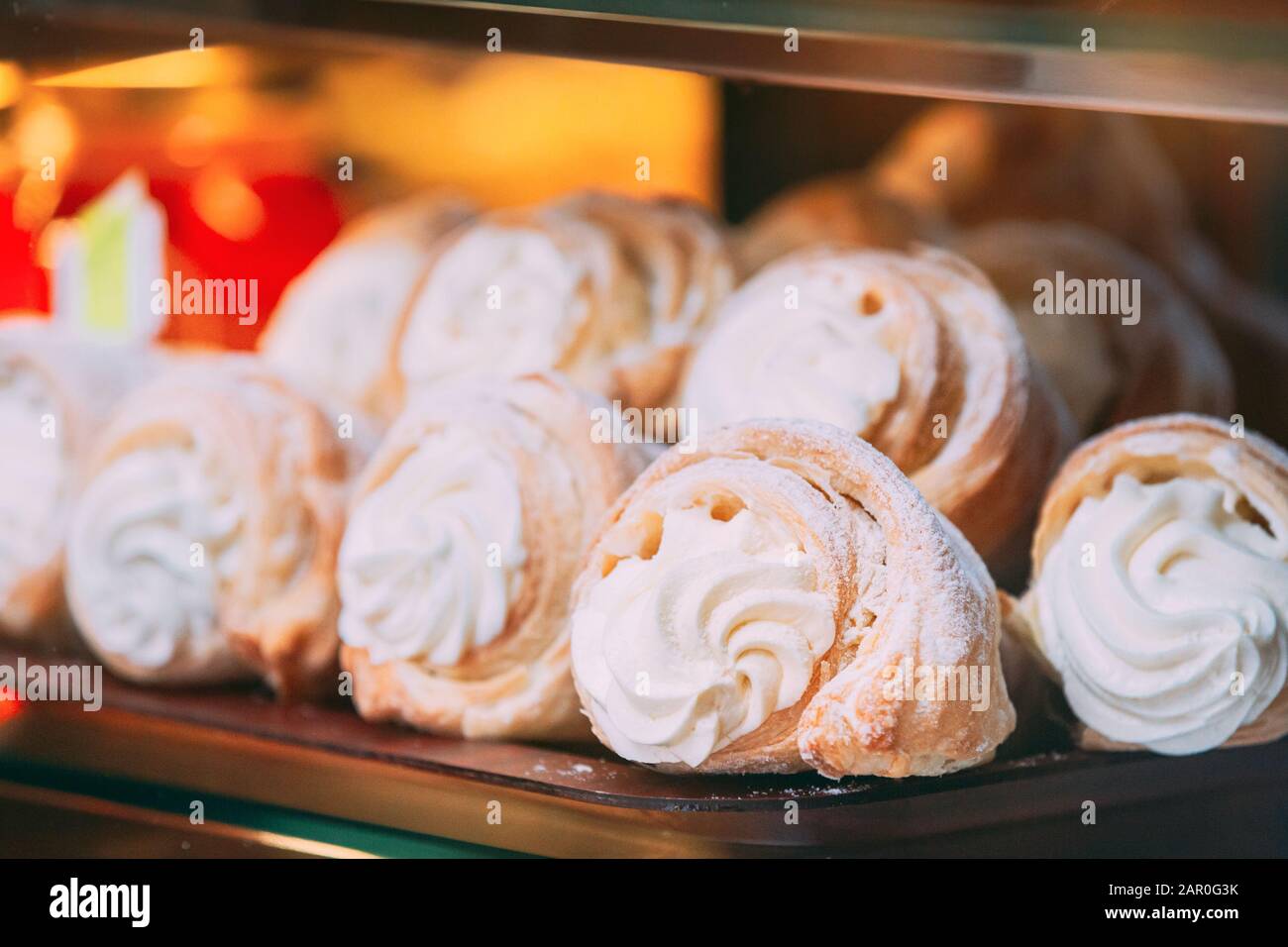 Frische, süße Kuchen mit weißer Pudding Sahne In Pastry Shop-Glas-Display. Stockfoto
