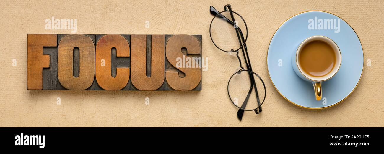 Zusammenfassung der Fokusworte in klassischen Holzbriefdruckblöcken mit einer Tasse Kaffee und Brille, Produktivität, Konzentration und persönlicher Entwicklung Stockfoto