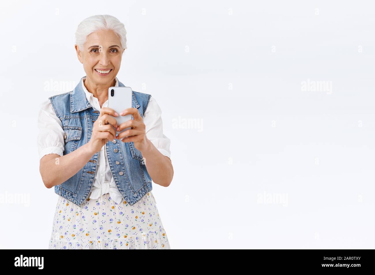 Charmante, moderne, stilvolle Seniorin, Großmutter verbringen Zeit im Vergnügungspark mit Enkelkindern, fotografieren von Kindern, lächeln als fotografieren, halten Stockfoto