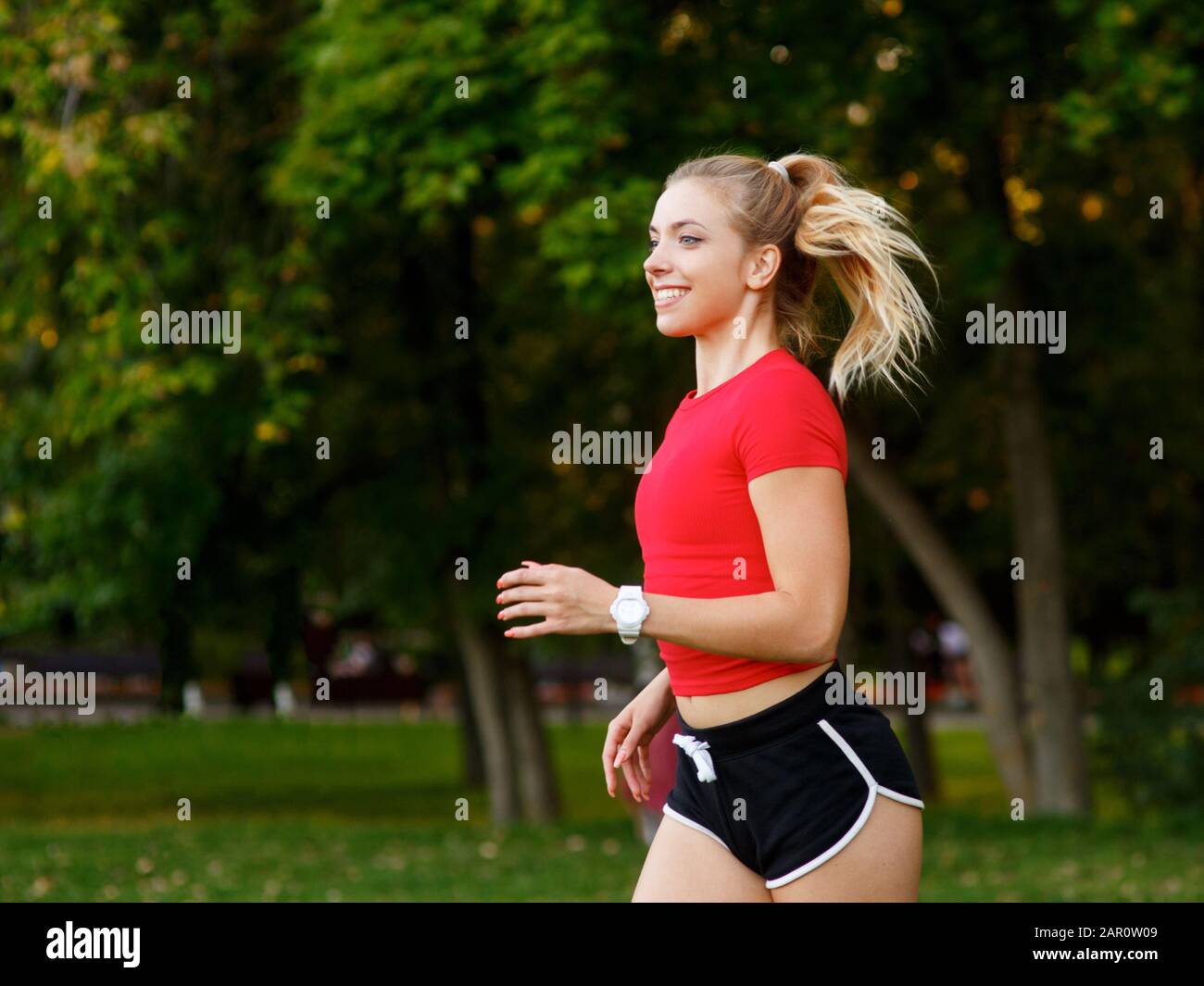 Ein junges Mädchen macht Sport im Freien, eine Frau in Shorts und ein rotes T-Shirt läuft in der Natur. Stockfoto