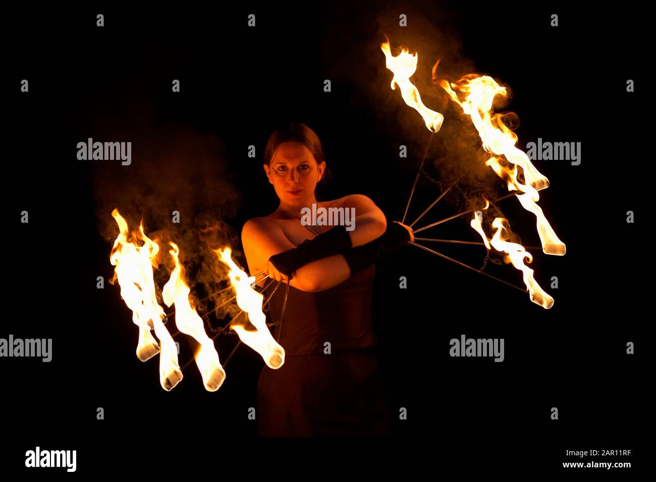 Weibliche Feuerdarstellerin mit brennenden Feuerventilatoren Stockfoto