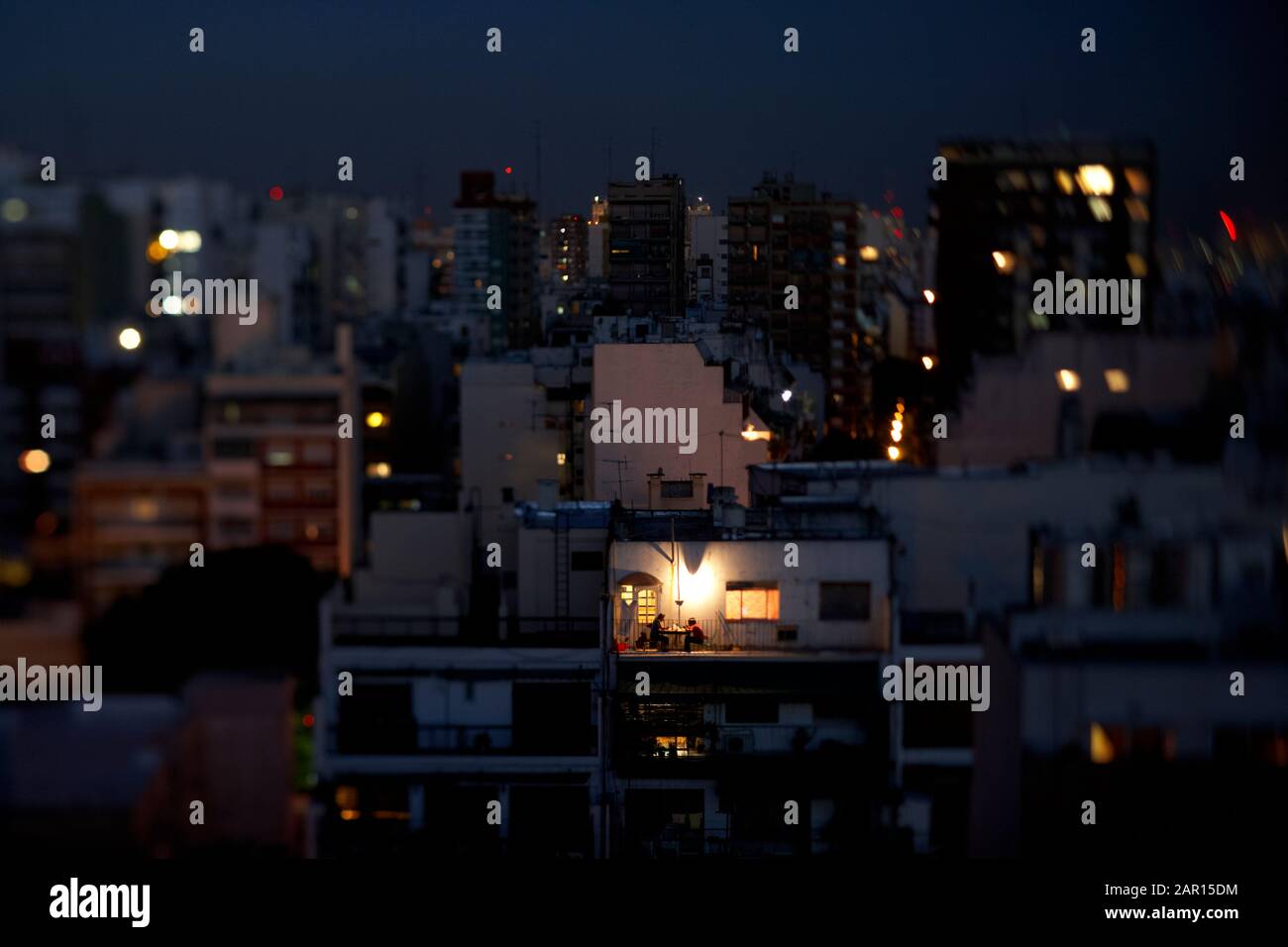 Ein Paar Abendessen auf der Dachterrasse eines Apartmentblocks mitten in der Stadt am Abend buenos aires argentinien mit Neige- und Schaltobjektiv Stockfoto