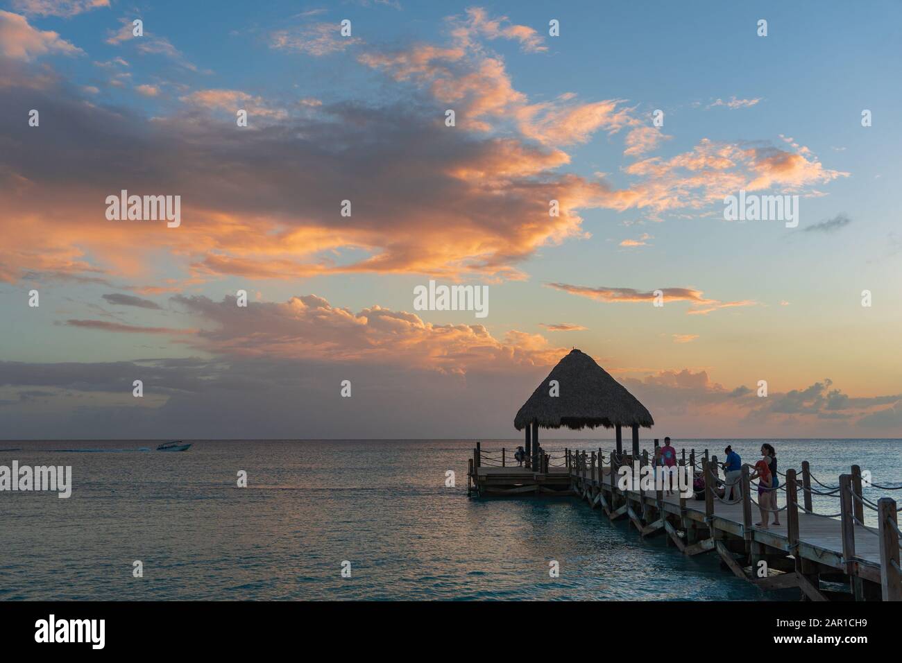 Karibischer Sonnenuntergang im Januar. Die Sonne malte die Wolken sanft orange. Stockfoto