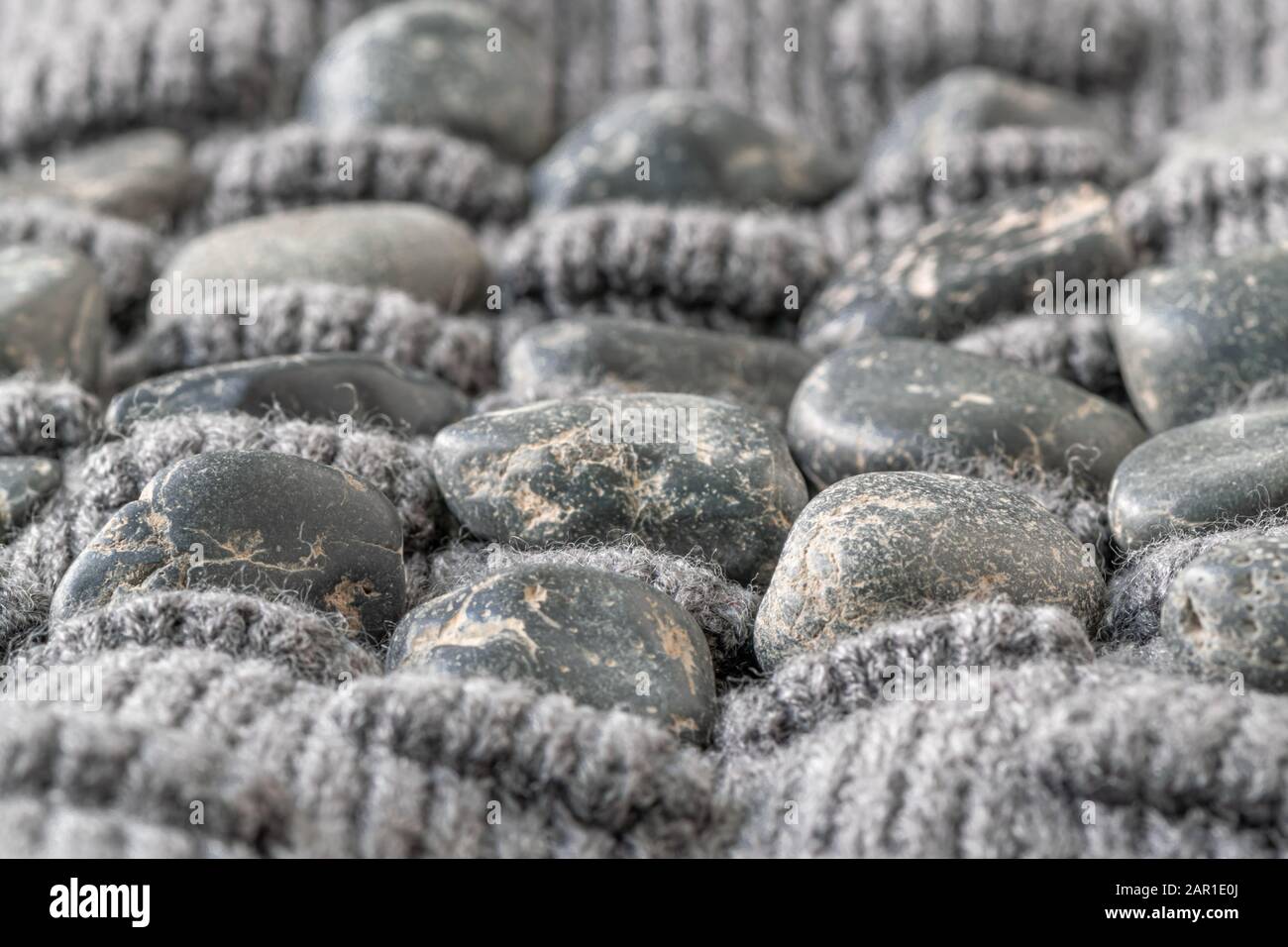 Gegensätze Pole. Robust und weich. Konzeptionell. Harte Steine und weiche Wollweben machen einen Weg. Köpfe und Enden jeder Situation. Stockfoto