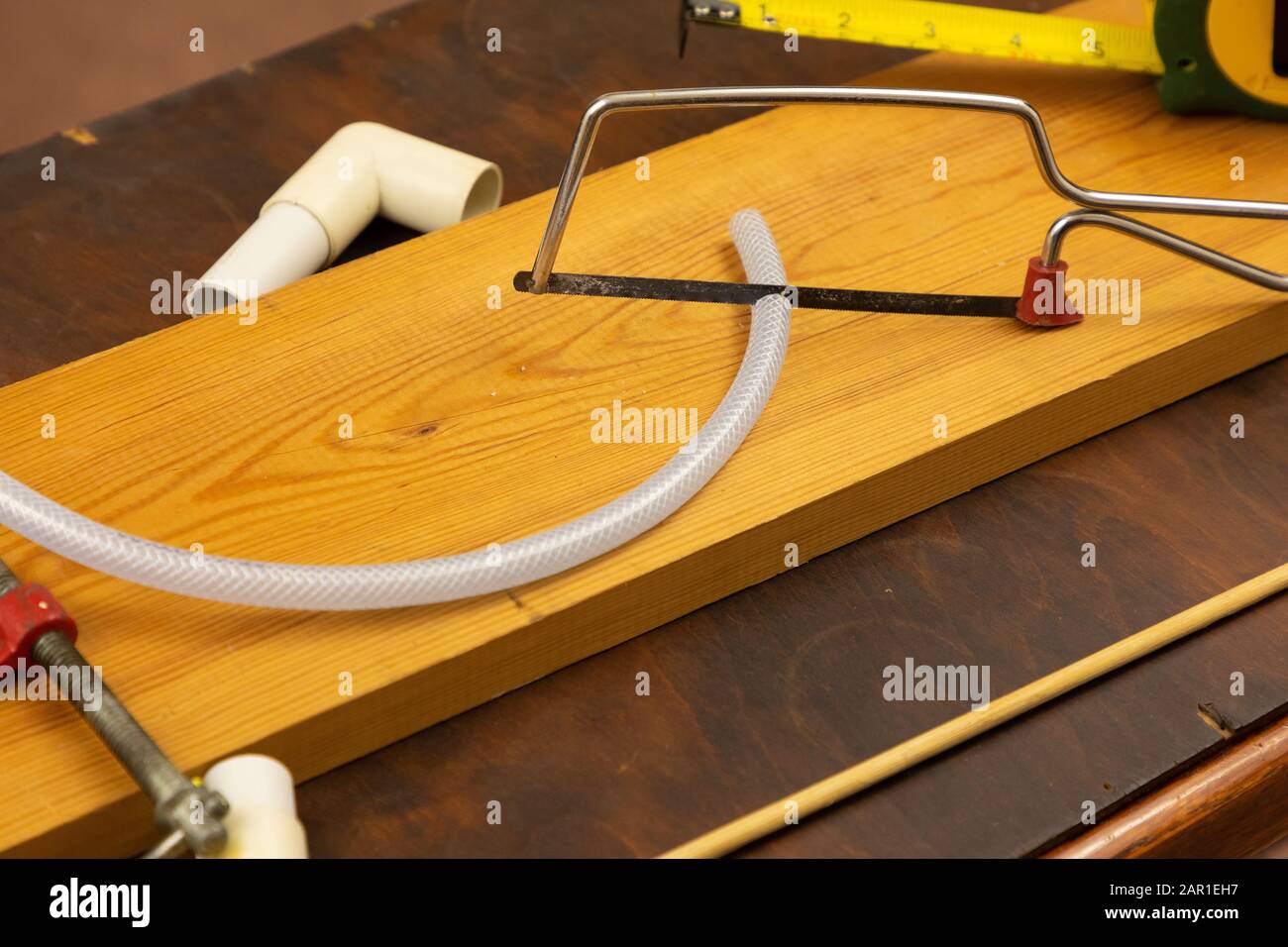 Mit einer Junior-Hack-Säge wird ein kleines Stück Kunststoffschlauch geschnitten Stockfoto