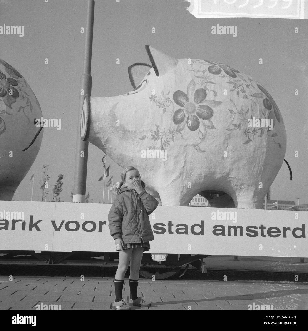 Aktion Zum Weltspartag. Zwei riesige Sparkassen auf Trailer mit dem Text: Sparkasse für die Stadt Amsterdam Girl vor den Sparkassen Datum: 25. Oktober 1965 Standort: Amsterdam, Noord-Holland Schlagwörter: Banken, Kinder, Paraden, Sparen Stockfoto