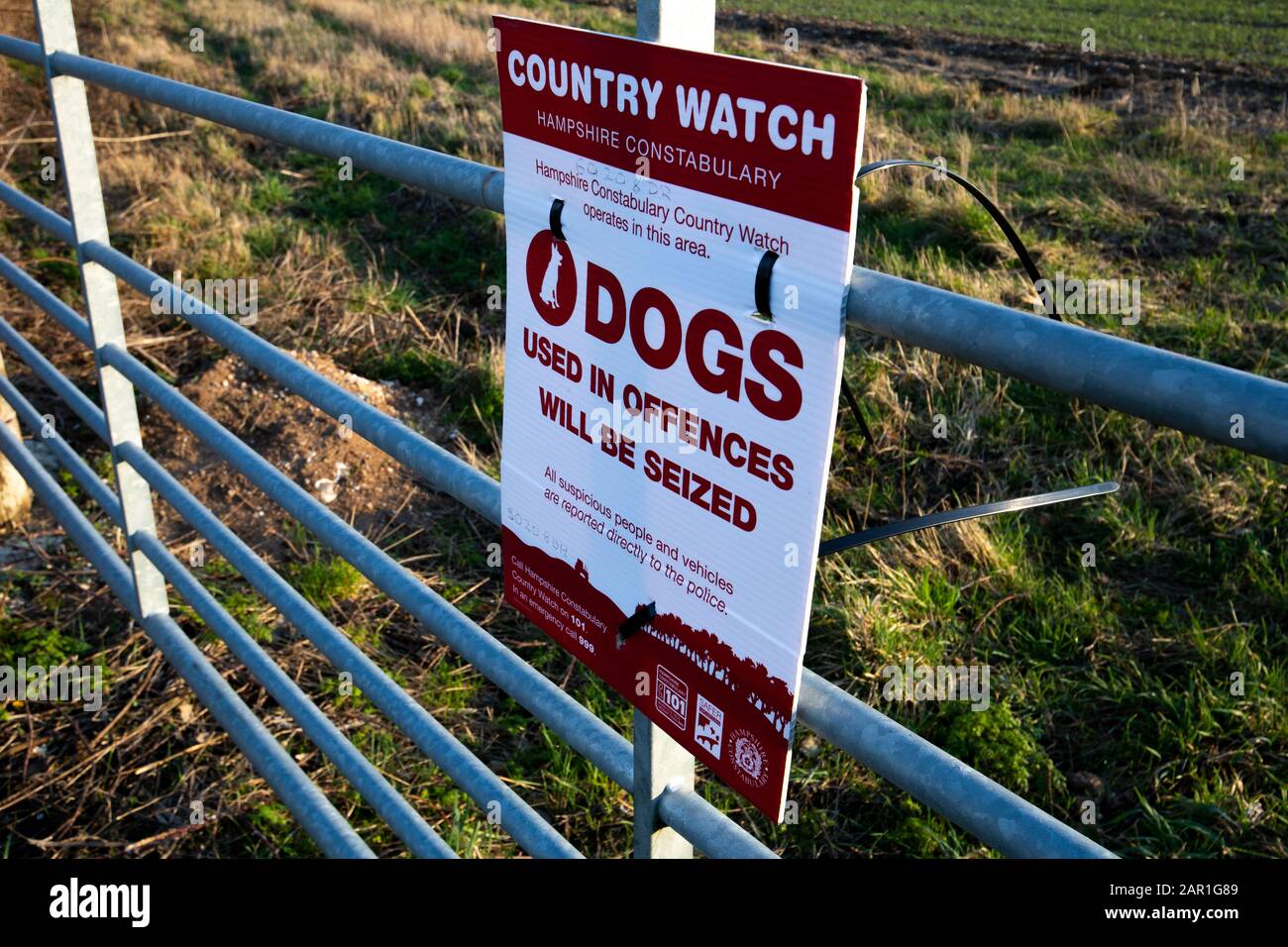 Die Landesuhr der Hampshire Constabulary arbeitet in diesem Bereich mit einem Hundeschild am Tor der Farm, um illegale Aktivitäten auf dem Land zu verhindern Stockfoto