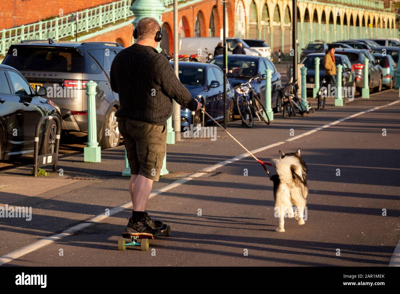 Mann Skateboarden in Brighton mit Hund Stockfoto