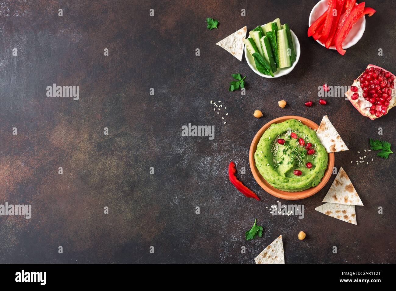 Grüne Avocado Hummusschale, gesundes veganes Bad. Biologischer grüner Kräuter, Spinathummus, mit Pita Brot und Gemüse verbreitet. Draufsicht, Kopierbereich. Stockfoto