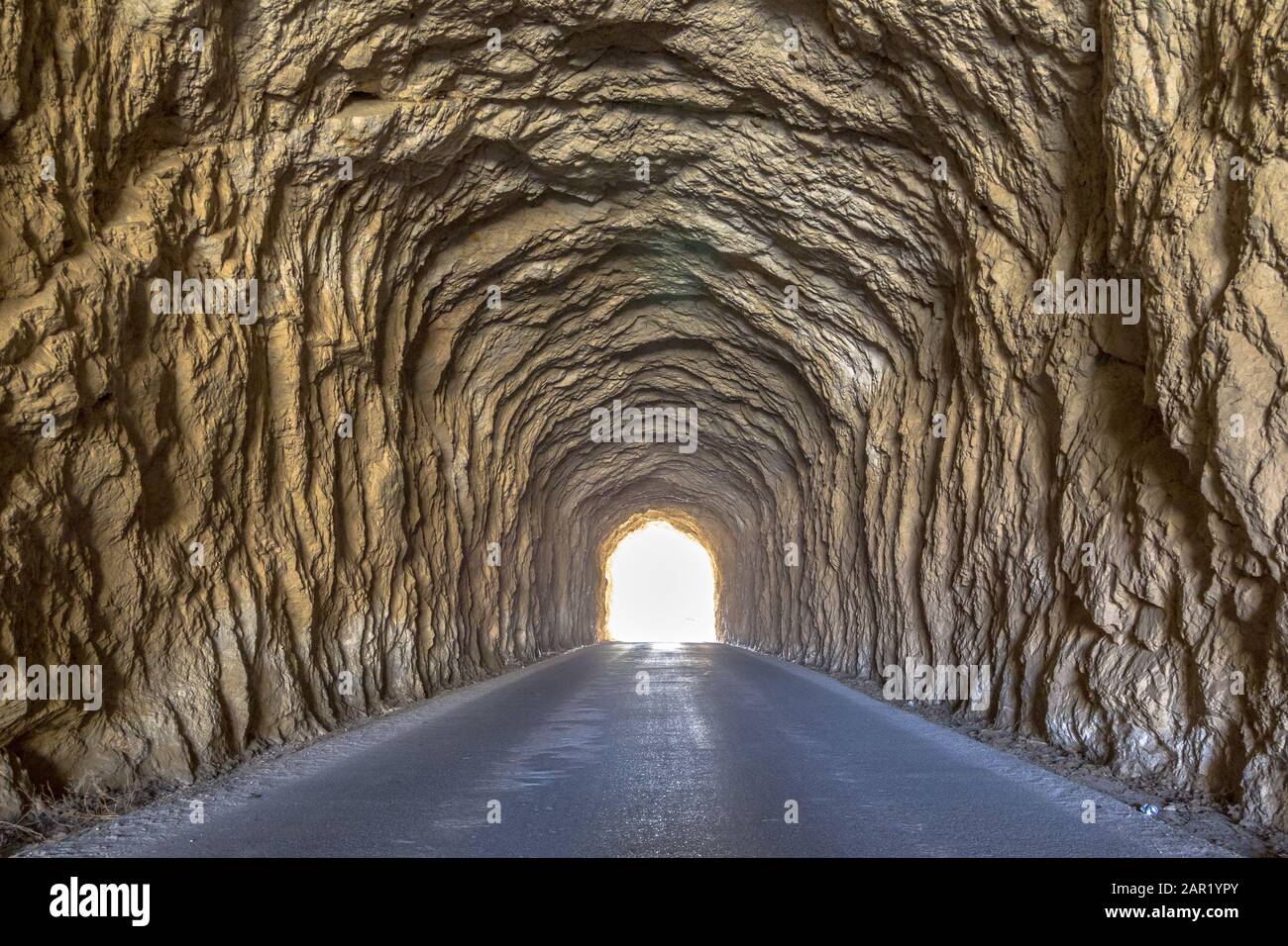 Helles Licht am Ende des Tunnels. Uralter Tunnel mit rauhen Wänden. Stockfoto