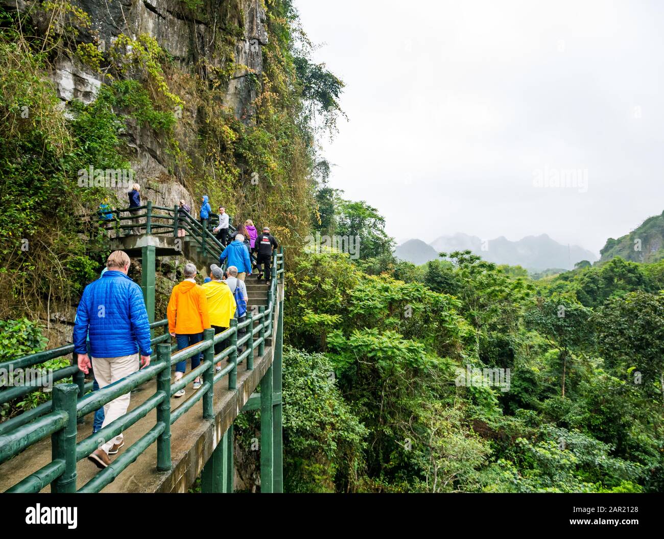 Touristen, die auf einem hochgelegenen Gehweg laufen, Grotten von Trung Trang bei nebeligem Wetter, Cat Ba Island, Halong Bay, Vietnam, Asien Stockfoto