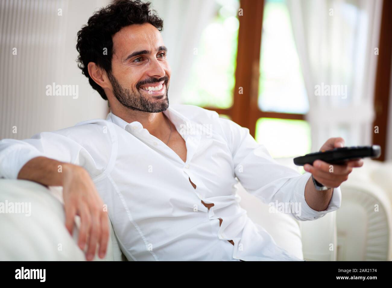 Mann auf der Couch schaltet die Fernbedienung TV-Kanäle Stockfoto