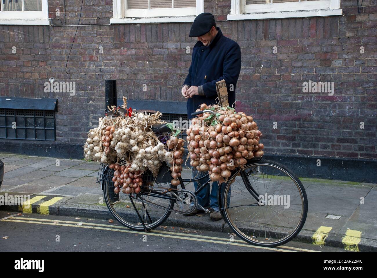 London, GROSSBRITANNIEN - 3. November 2007: Französischer Zwiebelverkäufer mit seinem Fahrrad mit Knoblauch und Zwiebeln Stockfoto