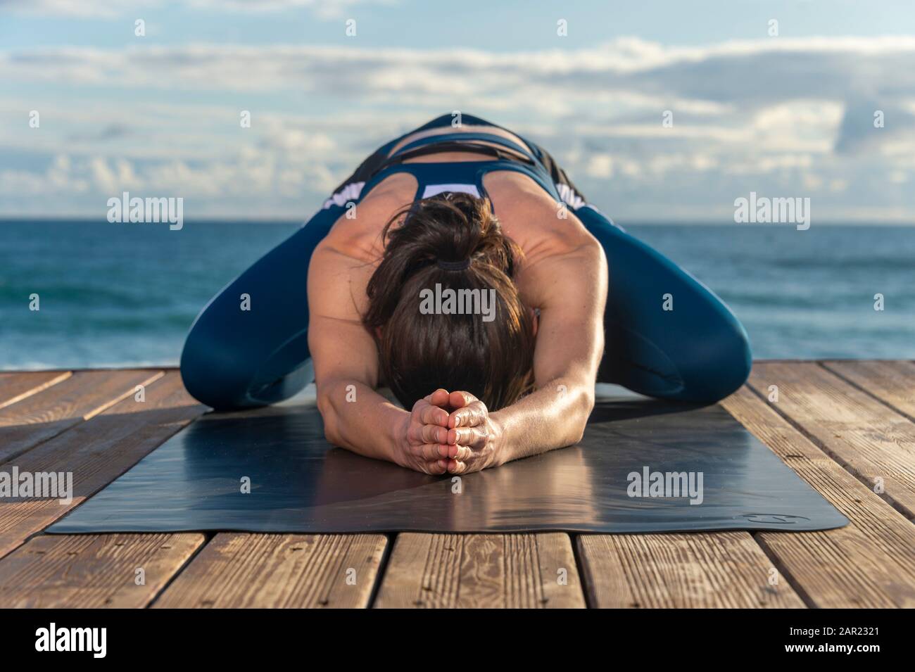 Frau, die Asana-Yoga-Pose des Kindes vor dem Meer praktiziert. Utthita Balasana posieren Stockfoto