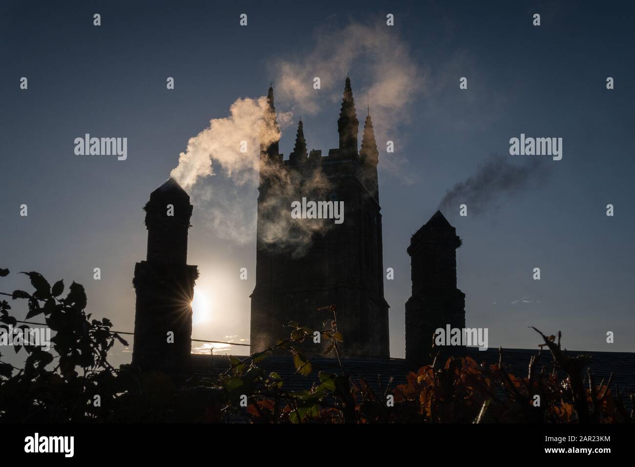 Ein trockener, heller Wintertag (Weihnachtstag) mit Blick auf die Pfarrkirche durch den Kaminrauch, Stoke Climsland, Cornwall Stockfoto