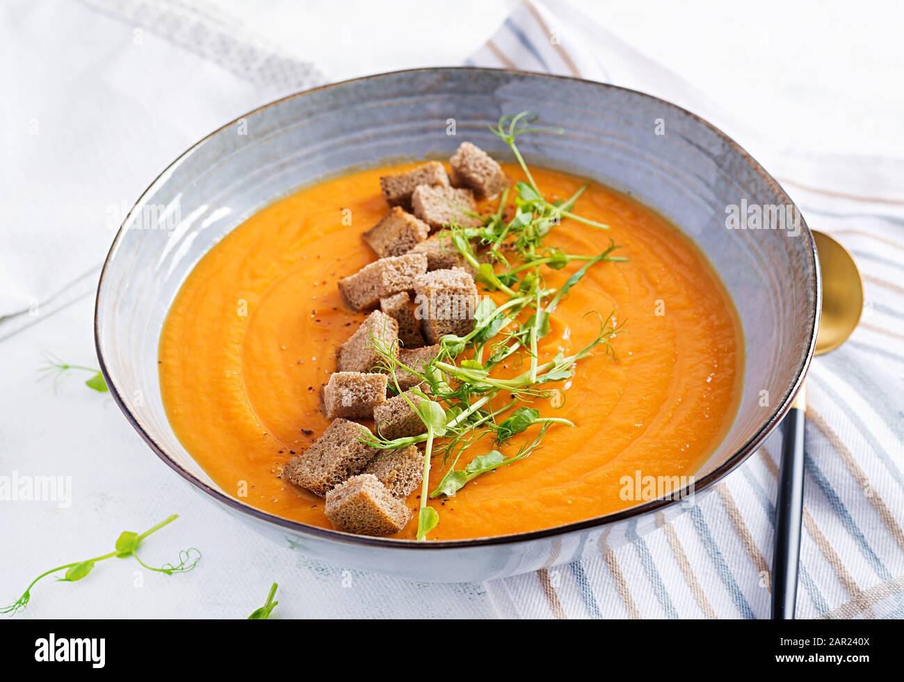 Kürbissuppe in einer Schüssel serviert mit Croutons und Erbsensprossen. Vegane Diätsuppe. Vegetarisches Essen. Stockfoto