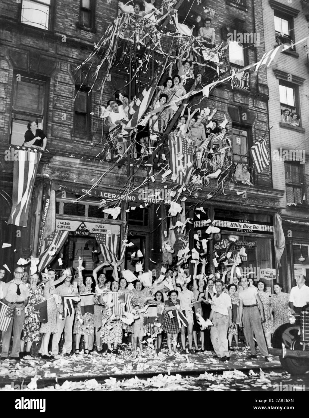 Freudige Einwohner Grußbotschaft über die japanische Annahme der alliierten Übergabebedingungen mit "Waving Flags and Confetti", 76 Mulberry St., Little Italy, New York City, New York, USA, New York World-Telegram und der Sun Newspapier Photograph Collection, 14. August 1945 Stockfoto