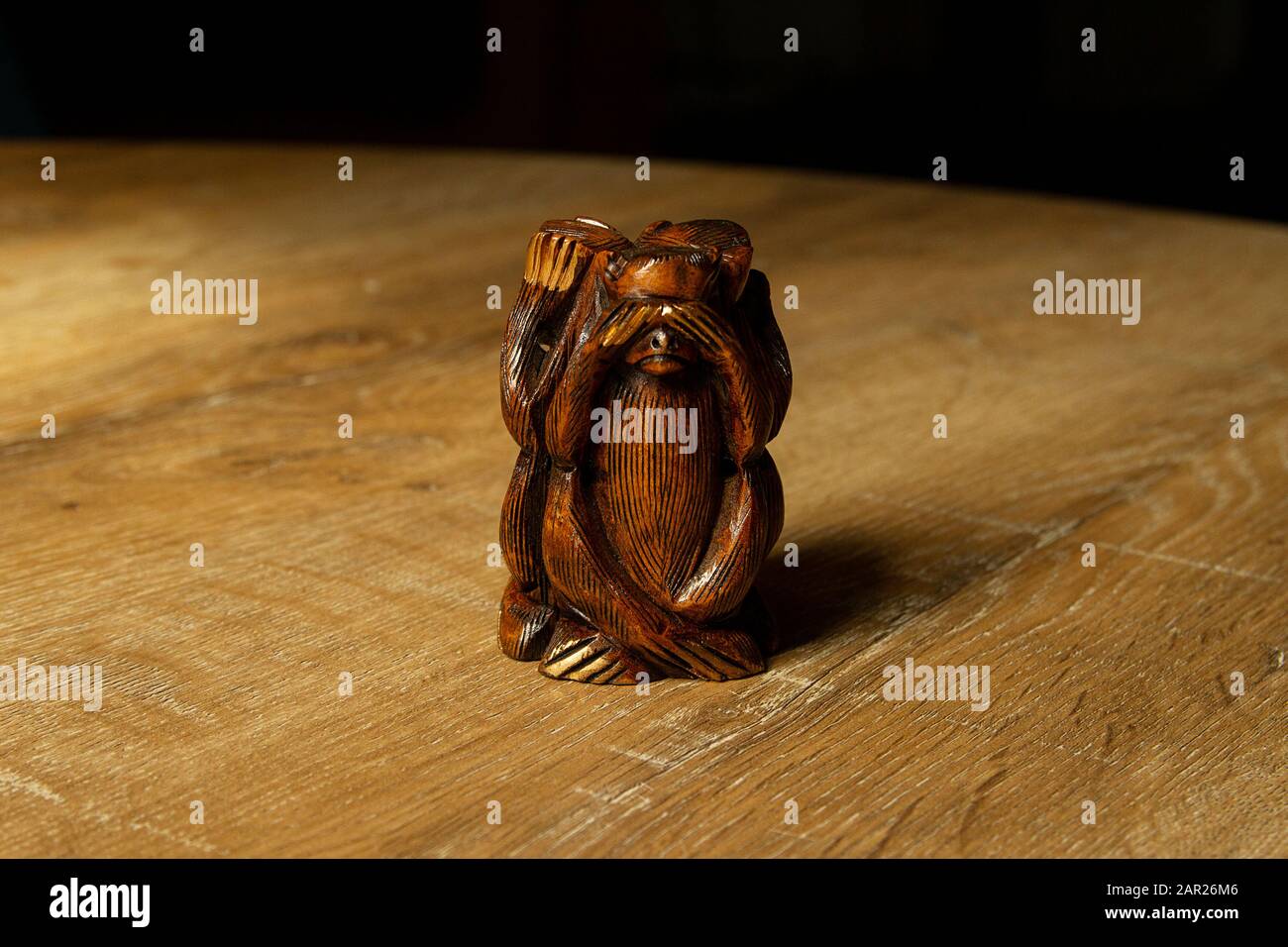 Mit verbundenen Holz-Affen-Figuren auf Holzhintergrund. Ich sehe es nicht. Drei Affen der Weisen - Figurin von Schimpfwörtern, die eine "siehe-keine-böse"-Haltung darstellen. Stockfoto