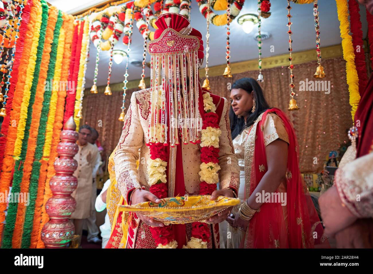 Ein Hindu-Bräutigam, der bei seiner Hochzeit in einem Tempel in Queens, New York City, eine traditionelle zerfranste Adresse trägt. Stockfoto