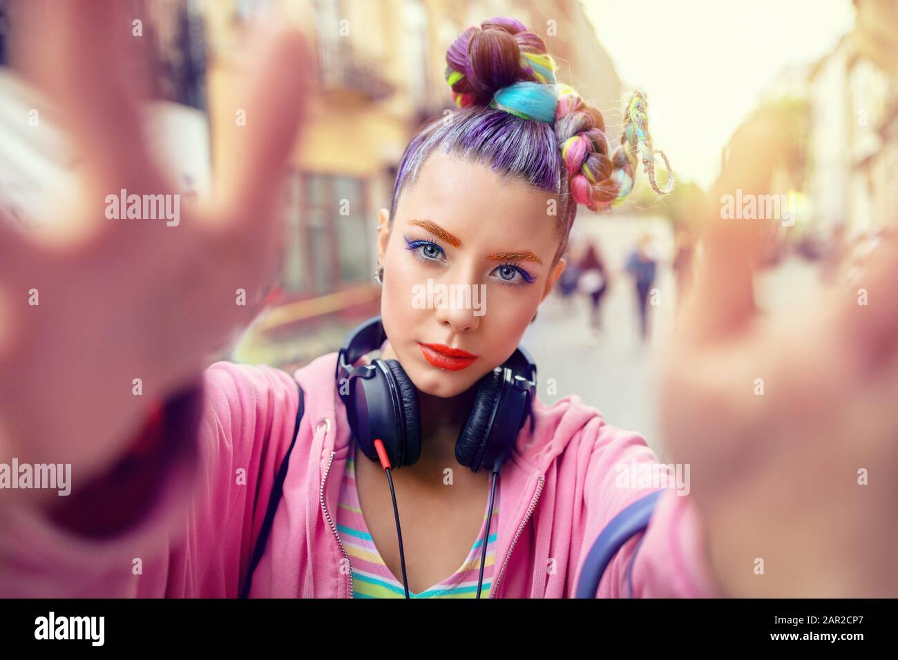 Verspieltes cooles hippy junges Mädchen mit Kopfhörern und verrückten Haaren, die selfie auf der Straße einnehmen Stockfoto