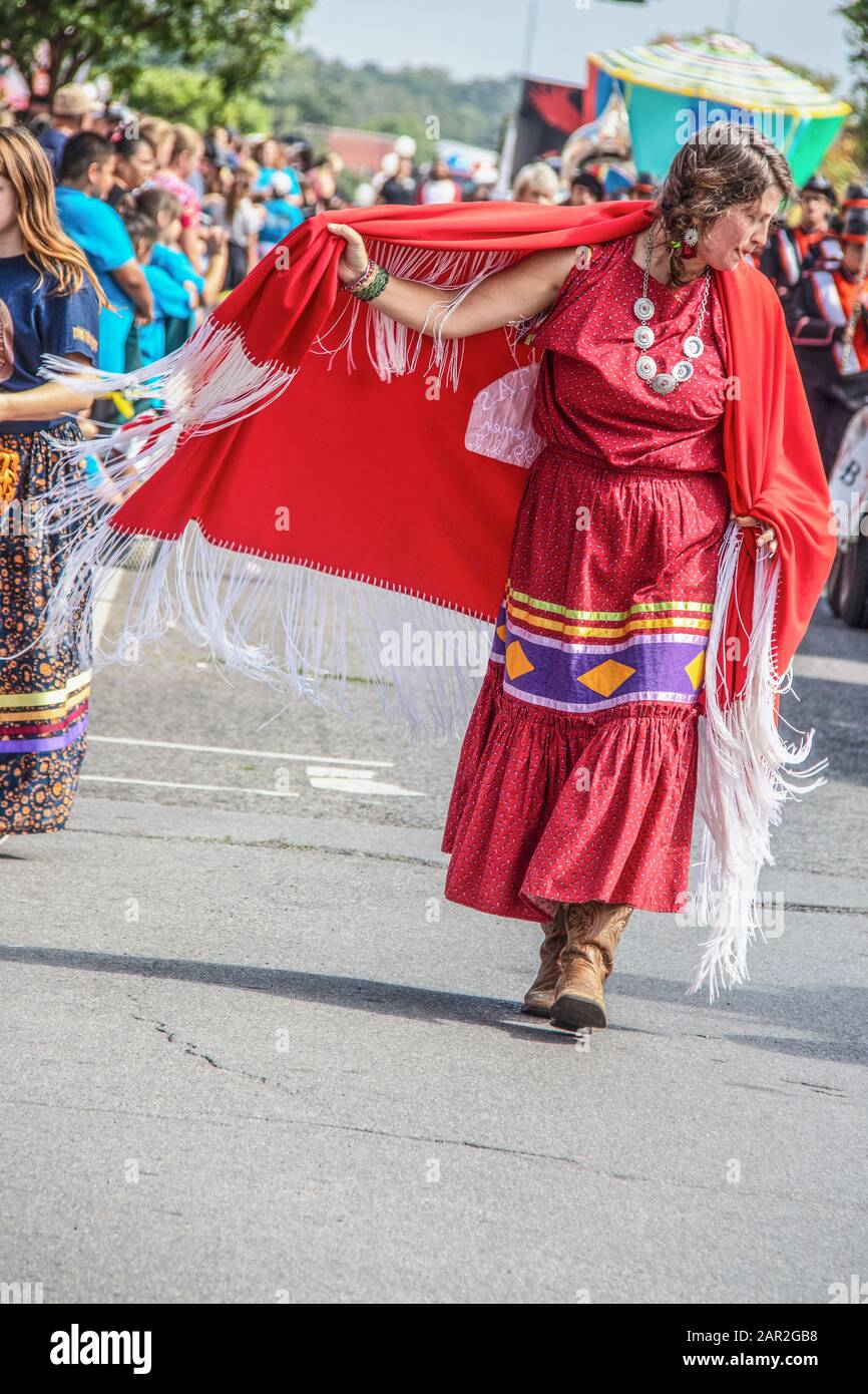 8-31-2019 Tahlequah USA - amerikanische Native Woman in traditionellem Kleid und Cowboystiefel wirbelt ihr rotes gefrantes kap auf, während sie in Cherokee National Ho spaziert Stockfoto