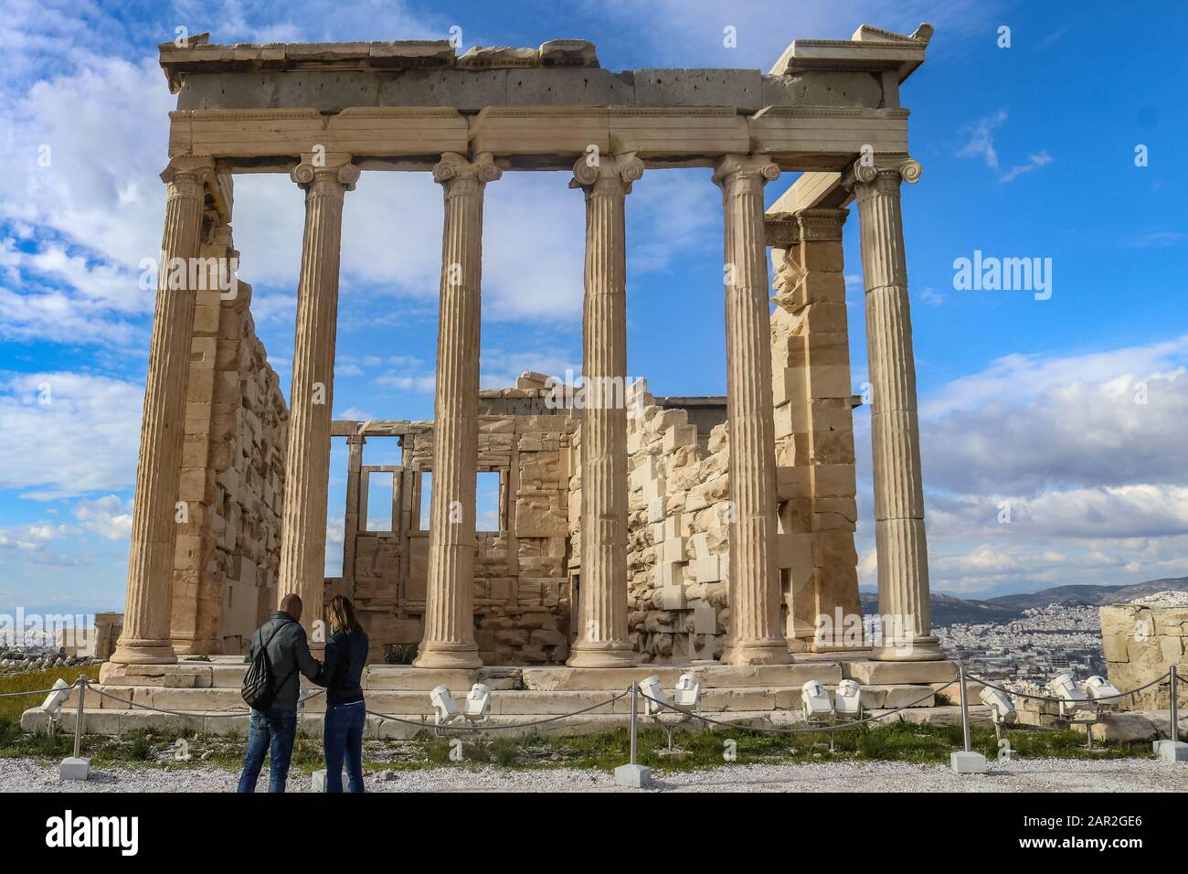 Der Tempel der Echtheion Akropolis Athen Griechenland mit zwei Touristen vor den Dächern Athens und einem wunderschönen Himmel im Hintergrund Stockfoto