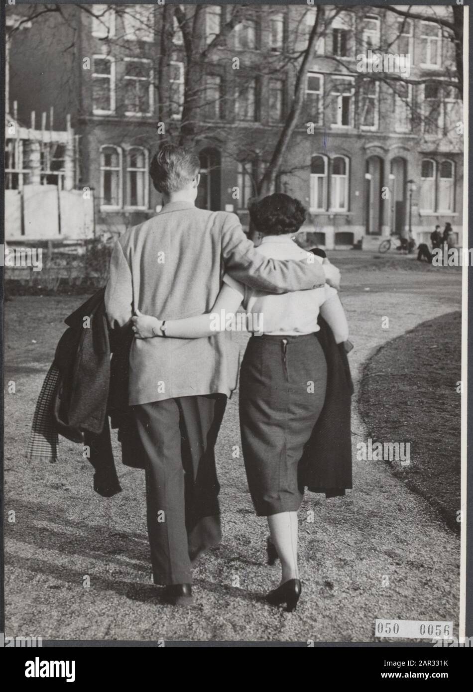 Das Quecksilber steigt plötzlich im Thermometer an. Dieses junge Paar hat die Wintermäntel während eines Spaziergangs durch den Park am 5. März 1954 über den Arm genommen Stockfoto