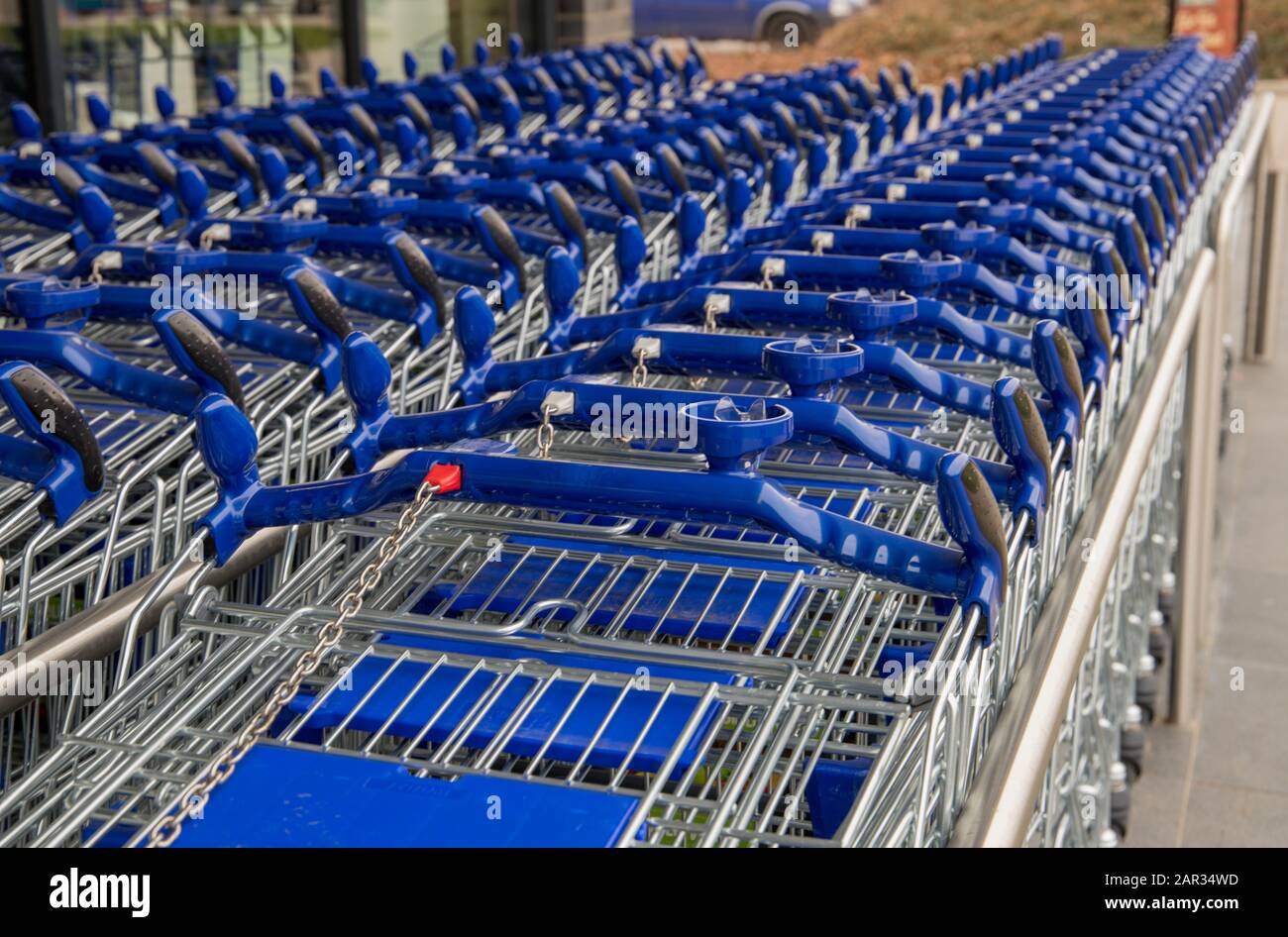 Blaue Einkaufswagen in einer Linie von vorne in der Nähe eines Supermarktes Stockfoto