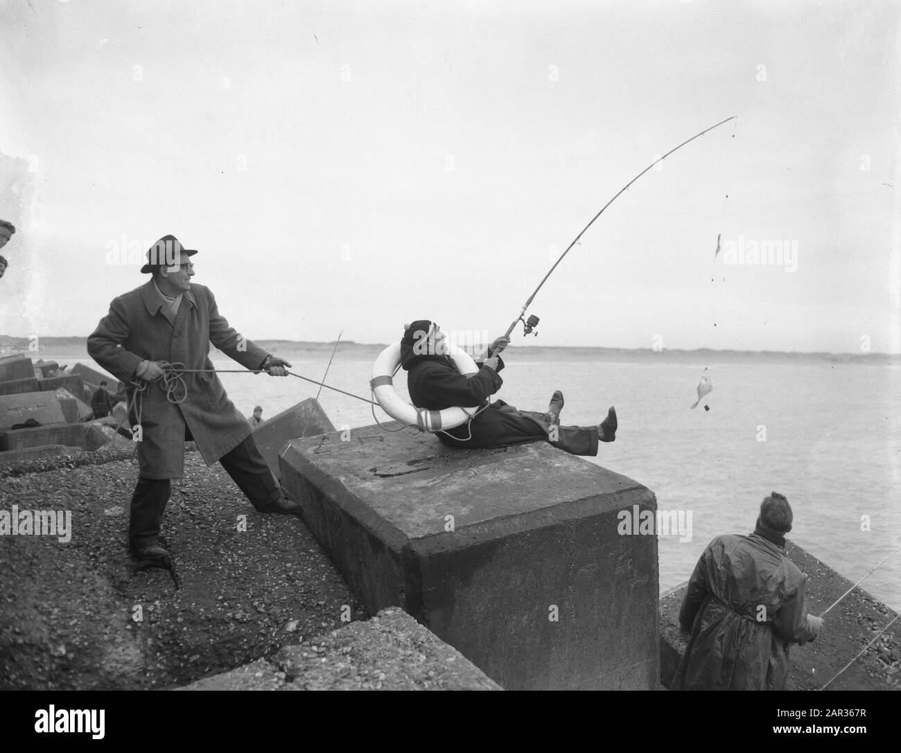 Angelausflüge Club der 100 Pier IJmuiden Max Tailleur en Cees de lange Datum: 15. März 1955 Ort: IJmuiden Schlüsselwörter: Angelsaison persönlicher Name: Cees de lange, Tailleur, Max: Noske, J.D./Anefo Stockfoto