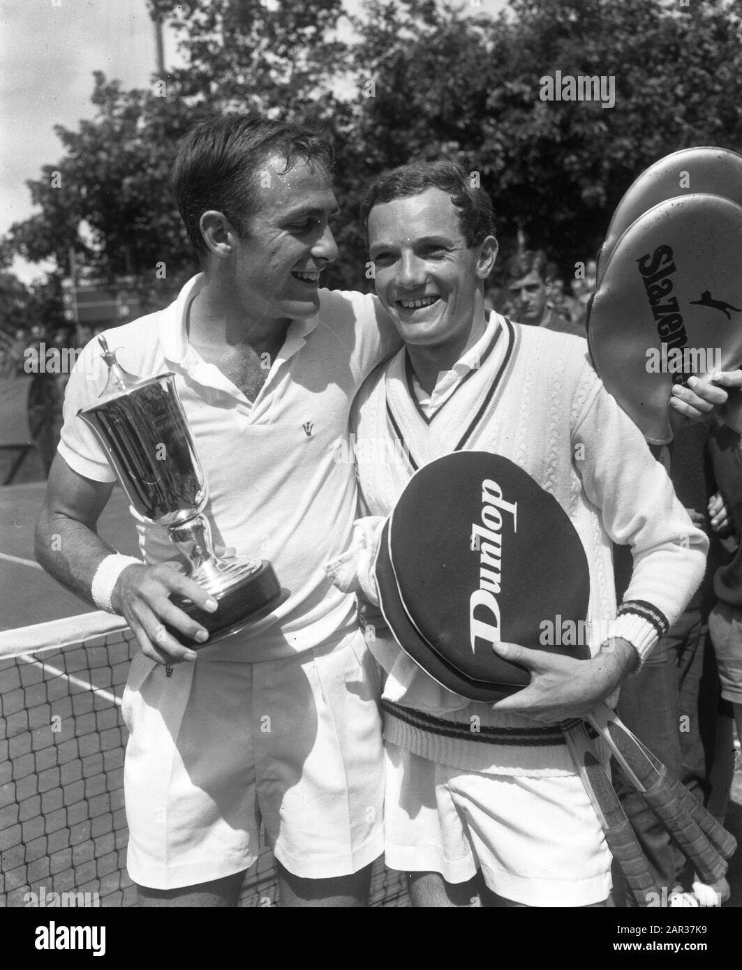 Tennis in Hilversum, der Gewinner des Herreneinzels John New Combe (Australien mit Pokal) Rechts Tom Okker Datum: 25. Juli 1965 Ort: Australien, Hilversum Schlagwörter: Tennis, Gewinner, Pokale persönlicher Name: Okker, Tom Stockfoto